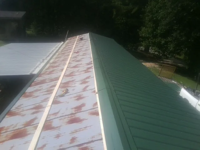 Old rusted panels beside newly installed green metal roofing — Wind Damage Roof Repair by Roofing Brothers in Elmwood